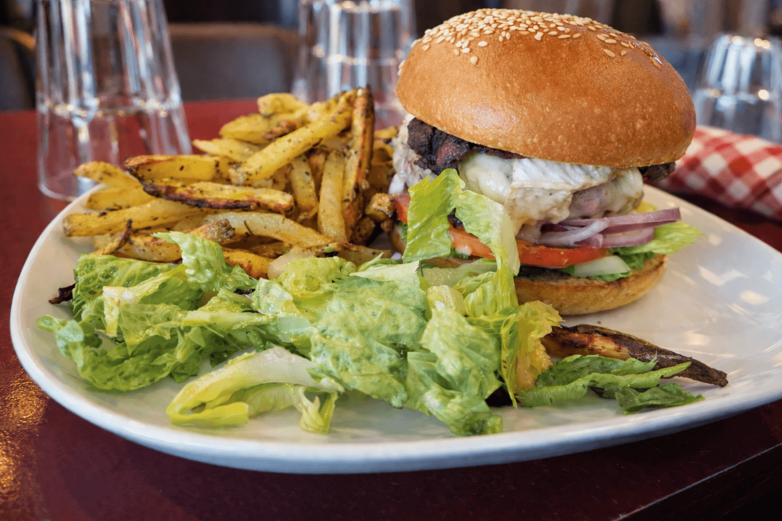 Un burger gourmet avec cheddar fondu, bacon et oignons rouges.